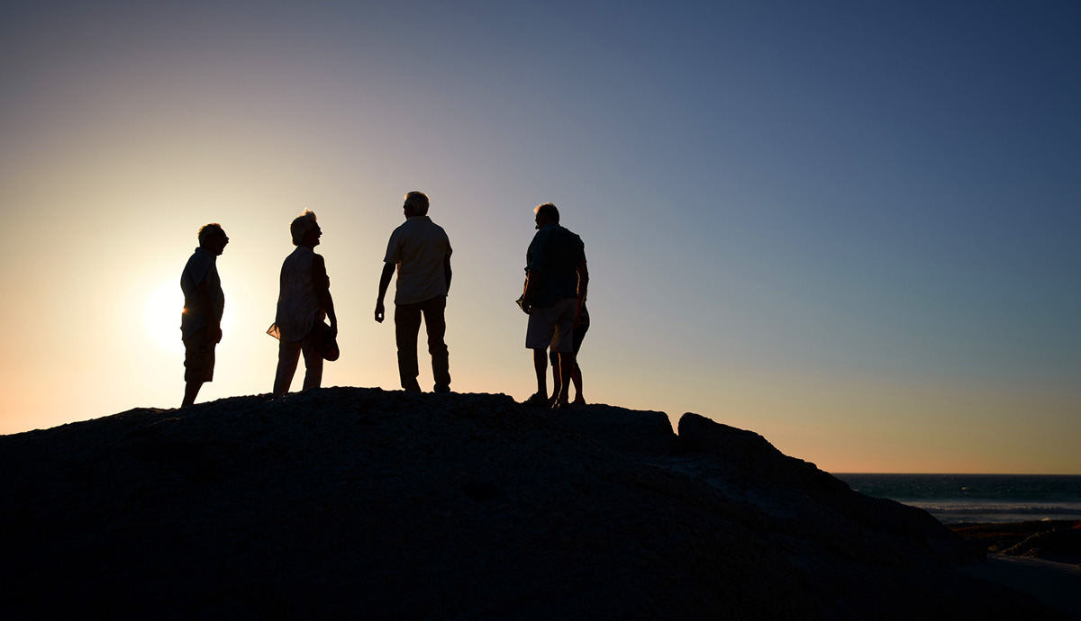 A photograph showing the outline of four friends on a hill as the sun sets.
