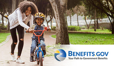An African American woman helps a child ride a bicycle alongside Benefits.gov's tagline: Your Path to Government Benefits.