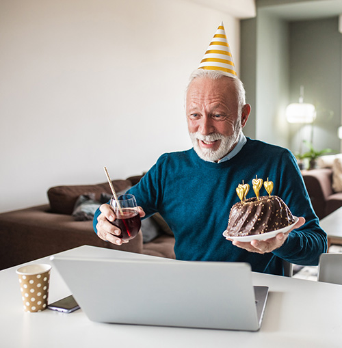 A man celebrating a birthday with a loved one on his laptop screen.