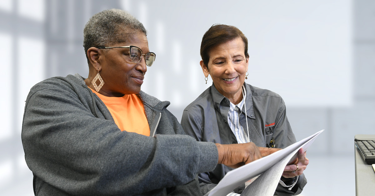 Image of a Tax-Aide volunteer helping a woman review tax documents