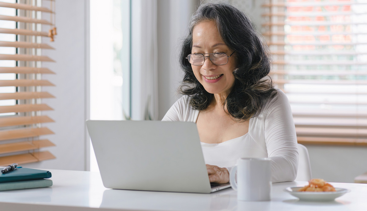 A woman wearing glasses works from home on her laptop.