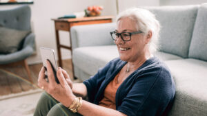 Woman in glasses looking at her phone and smiling.