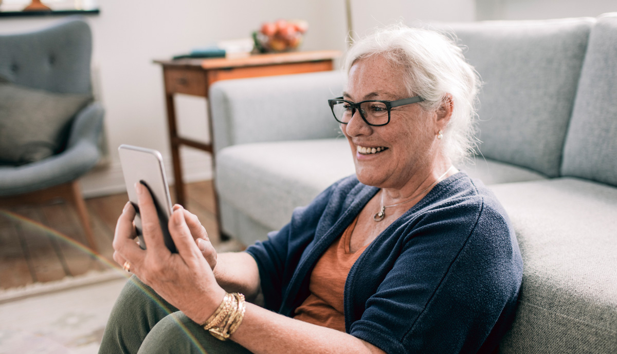 Woman in glasses looking at her phone and smiling.