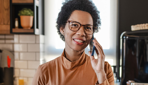 Woman wearing dark colored glasses while talking on cell phone