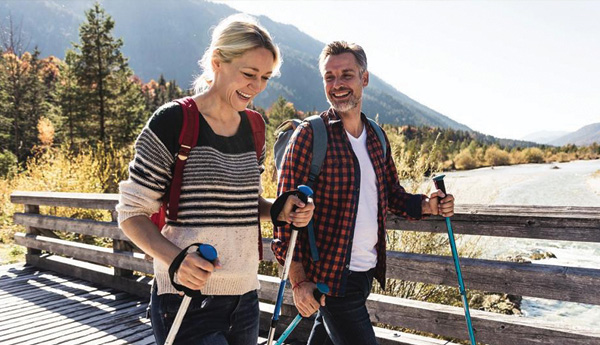 A man and a woman use trekking poles on their outdoor hike.