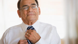 A man wearing glasses straightens his tie