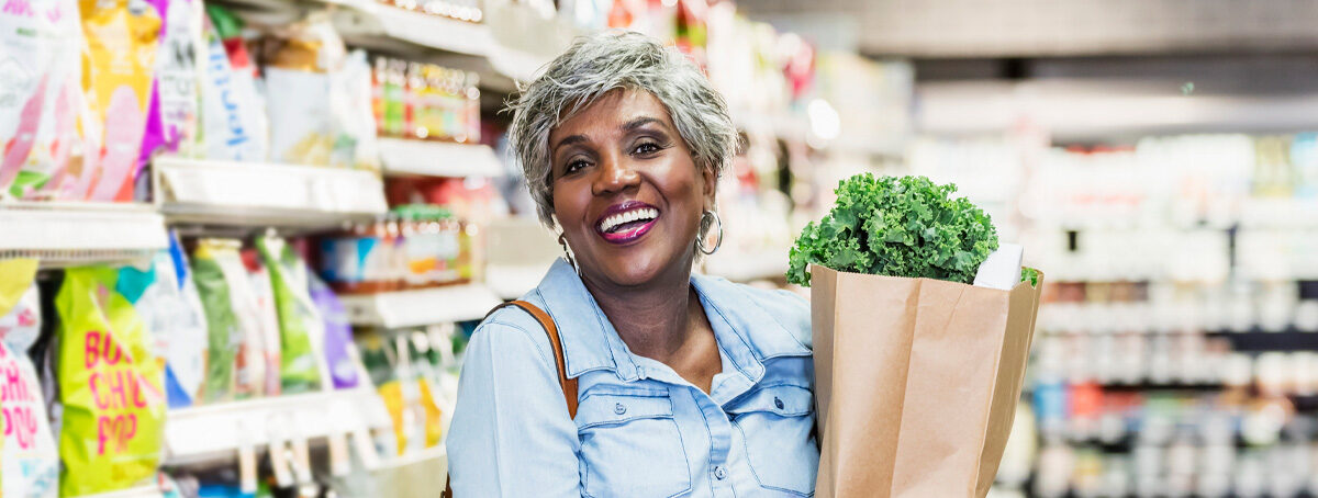 Image of a woman smiling in a grocery store holding a bag