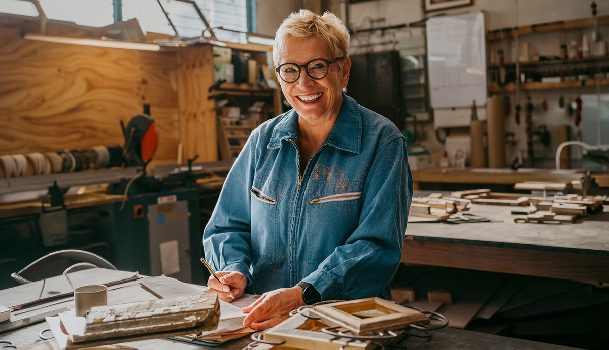 Person in a denim shirt, smiling, standing in front of a table in a garage workstation.
