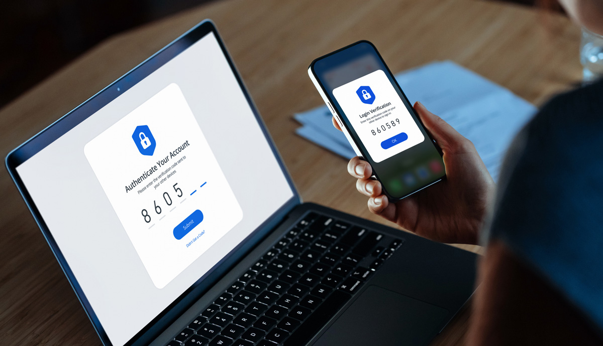 Over the shoulder view of a woman using mobile device with Two-Factor Authentication while logging in securely to her laptop. Over the shoulder view of a woman using a mobile device with Two-Factor Authentication while logging in securely to her laptop.