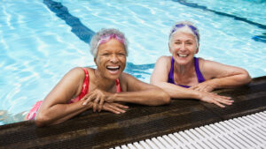 Two smiling mature women in a pool.