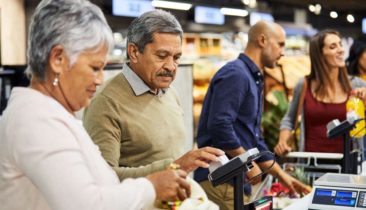 An older couple paying for their groceries at a store register