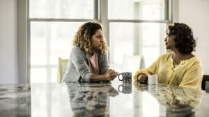 A daughter and mother share a conversation over coffee.