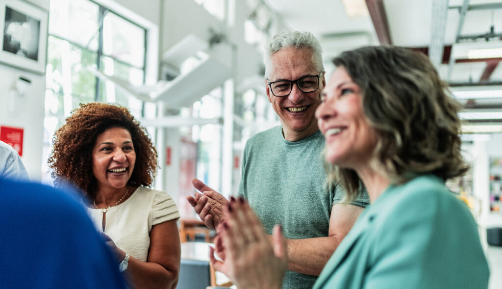 A diverse group of older adults network in a lobby space.