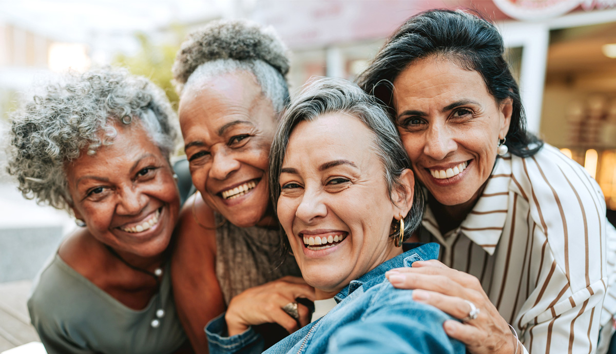 A close-up of four women huddled close together smiling at the camera