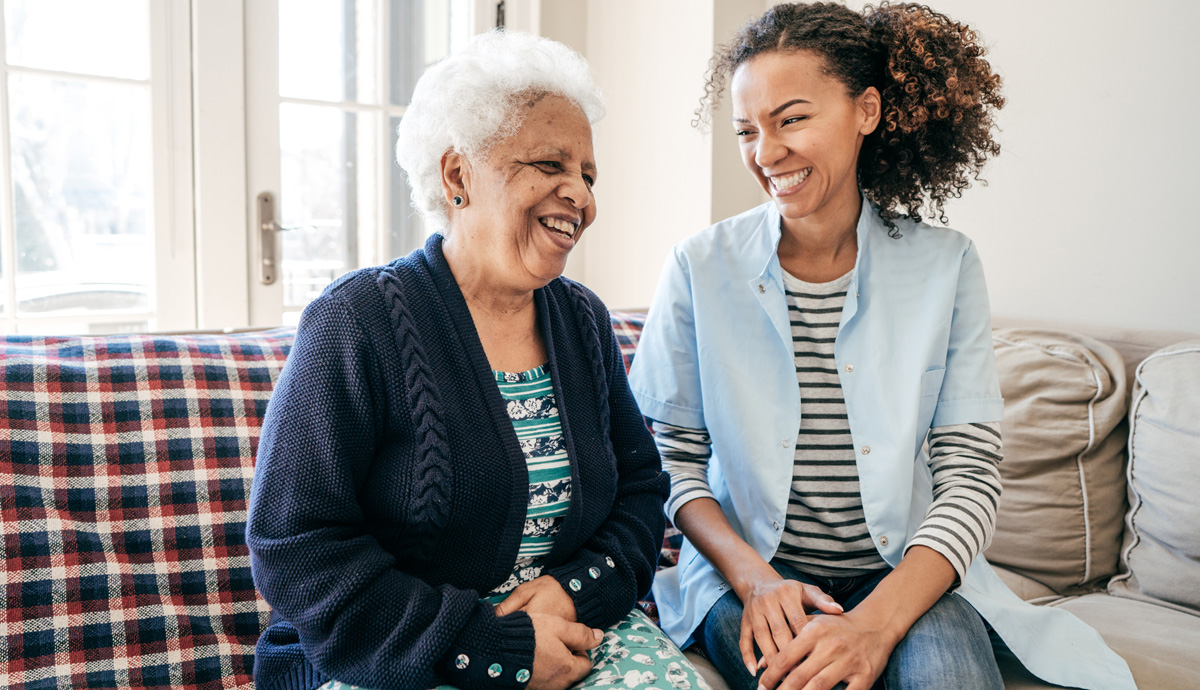Two women sitting on the couch smiling and laughing
