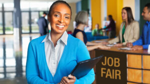 Women wearing a business casual outfit holding a clipboard at a job fair.