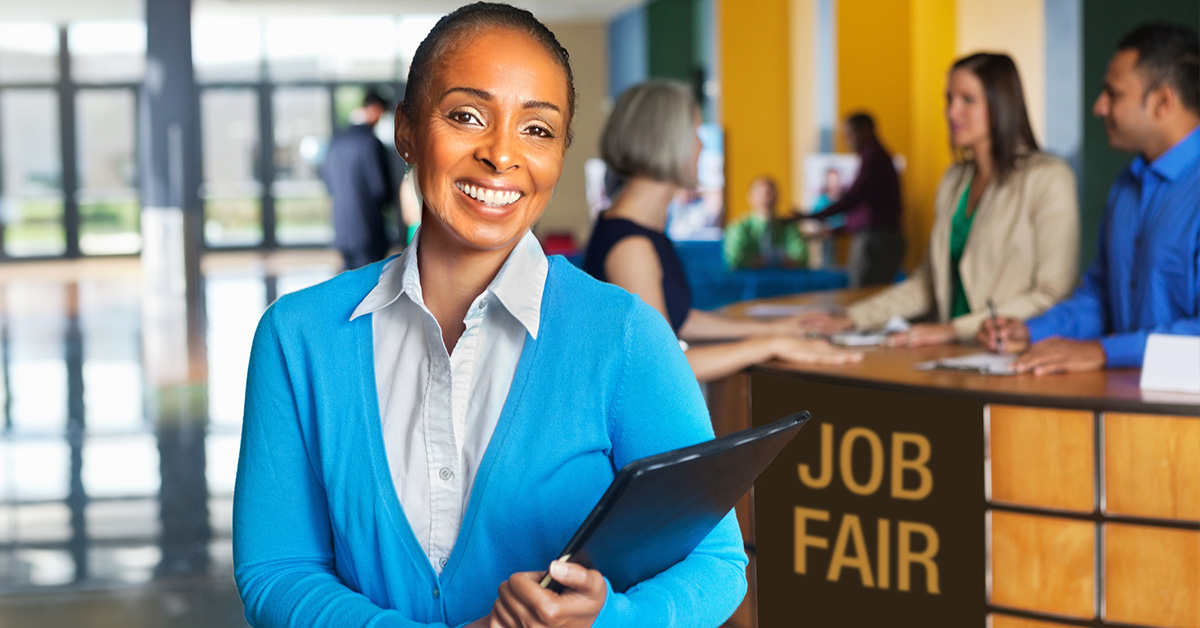 Women wearing a business casual outfit holding a clipboard at a job fair.