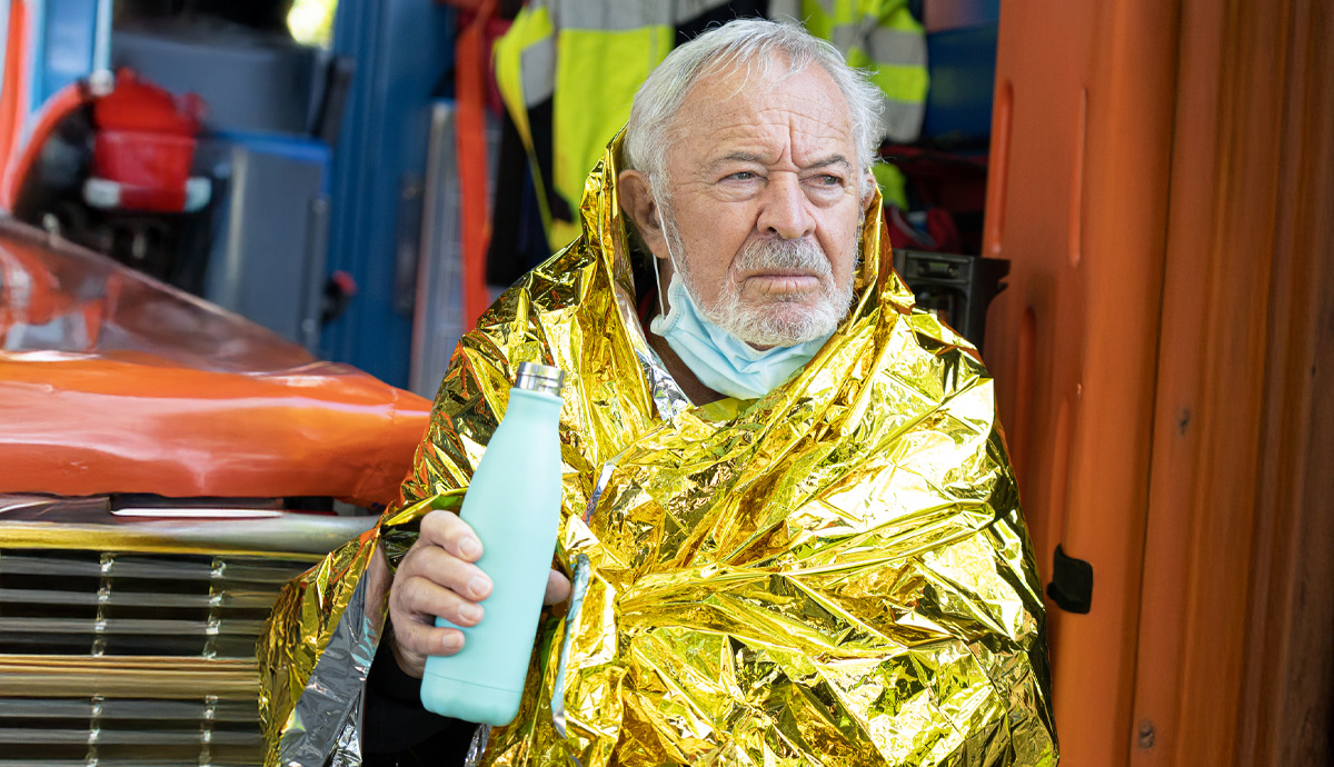 Image of a man in an emergency blanket with a bottle of water