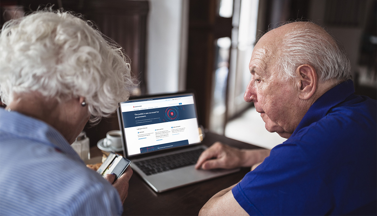 Image of a man and woman looking at a laptop with the Login.gov home screen