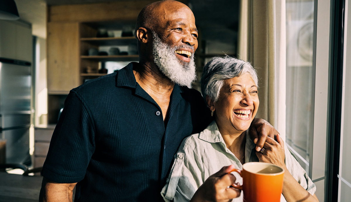 Image of an older happy couple, looking out the window laughing.
