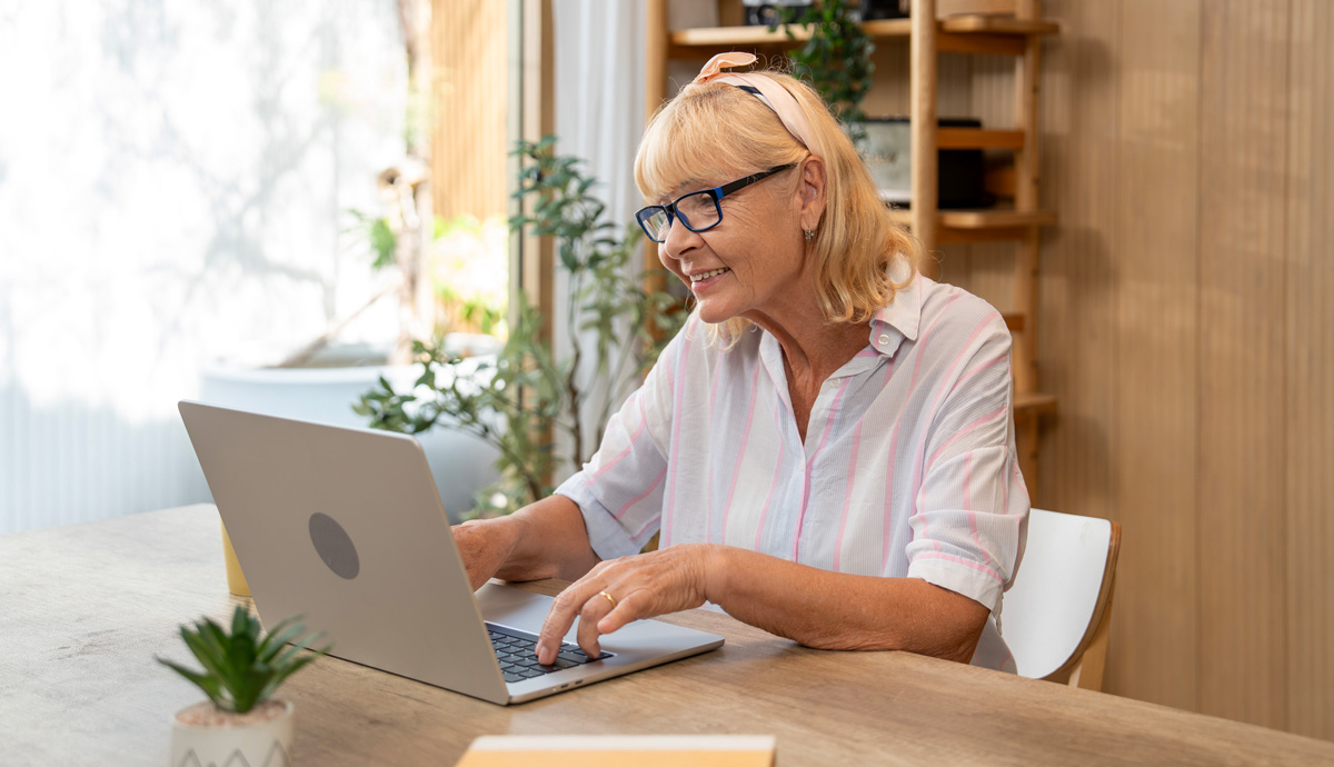 A smiling woman sits at a laptop